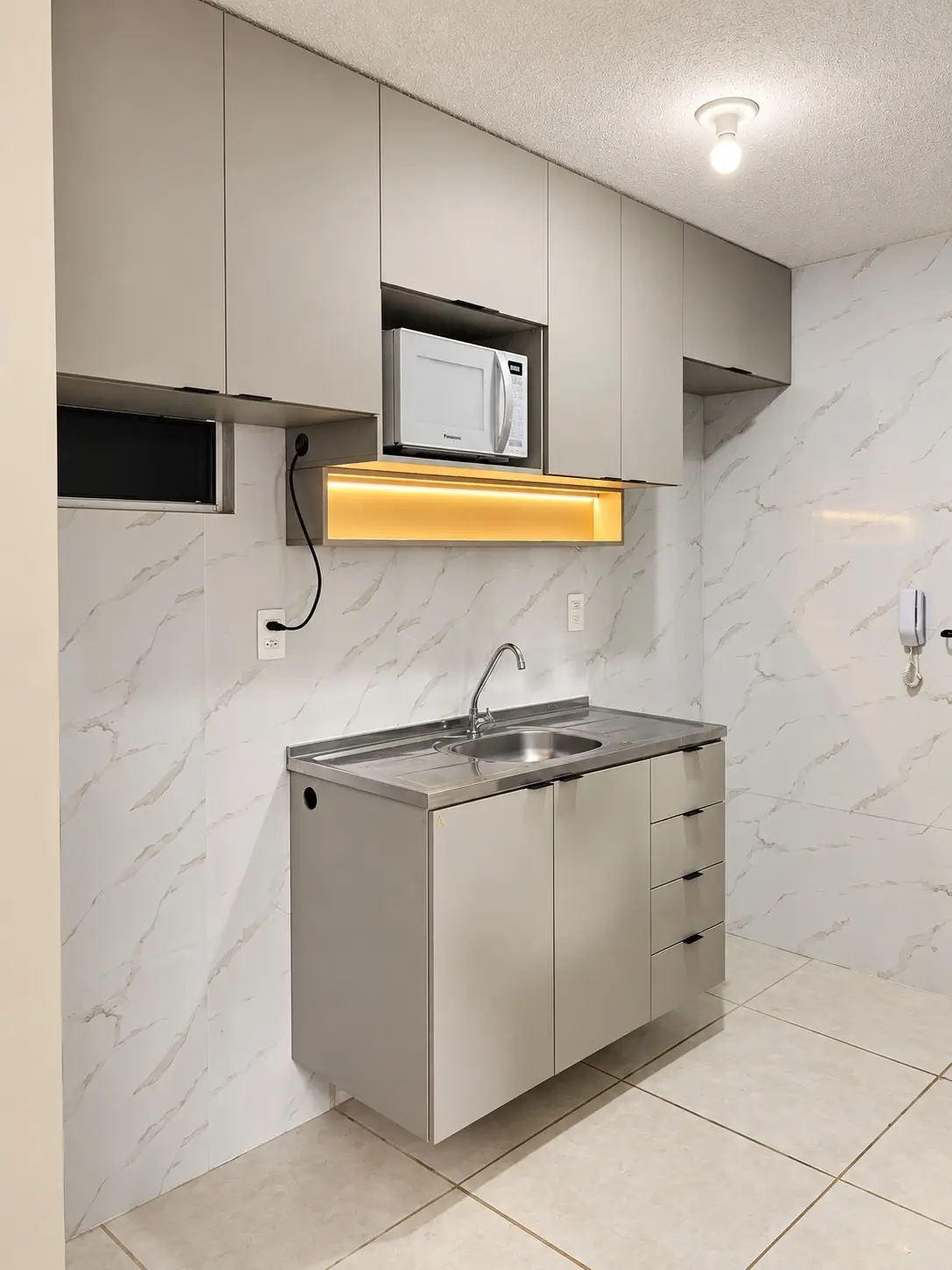 Área de serviço planejada sob medida em laca fendi, com torre de embutir e bancada de inox