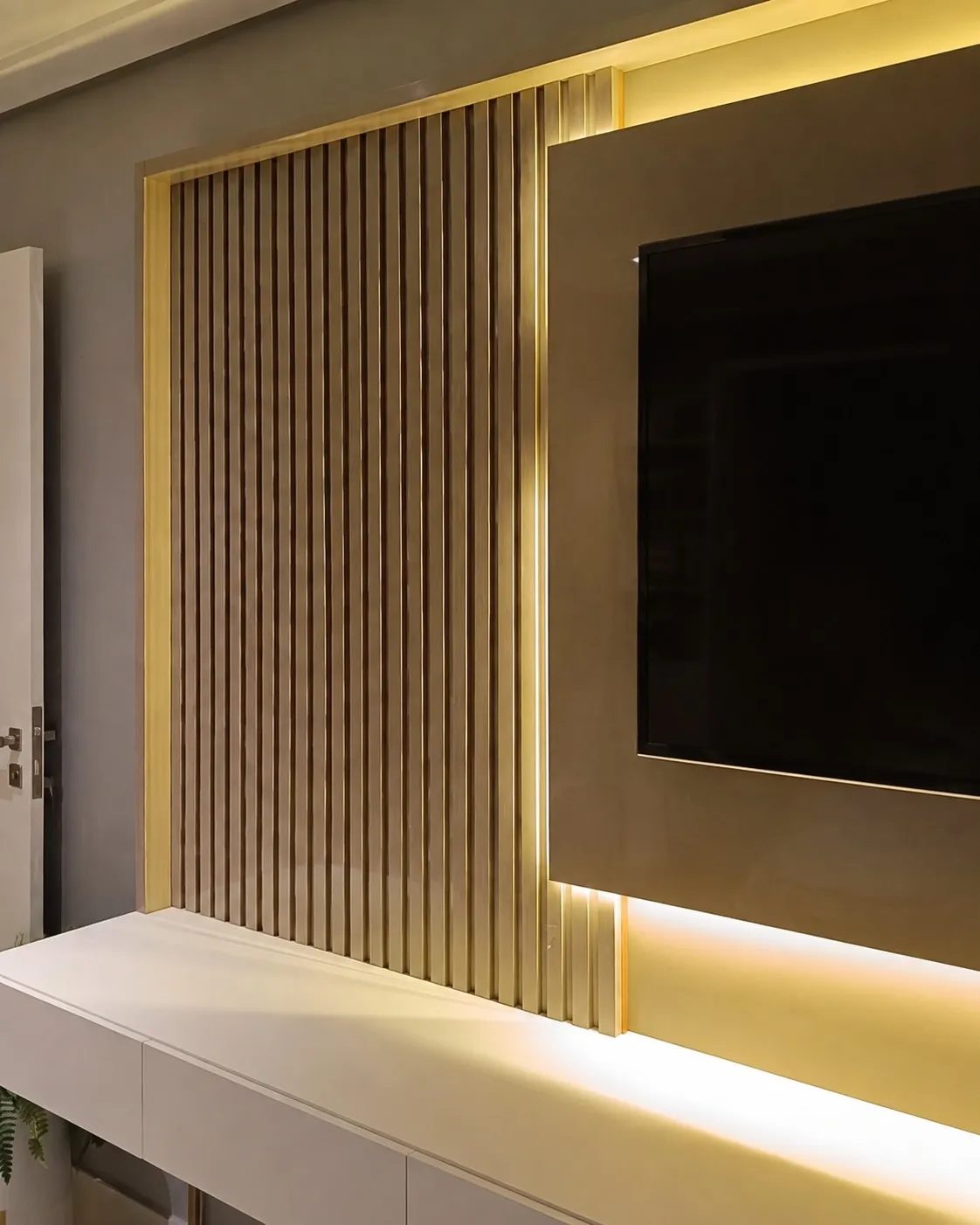 Detalhe do perfil de latão entre o ripado e a laca do painel, com fita de LED embutida